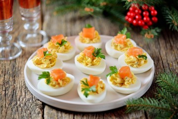 Stuffed chicken eggs with soft cheese, capers and salted salmon. Christmas background.