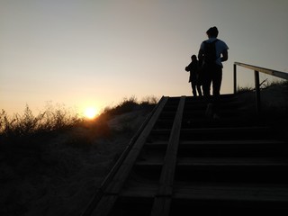 Two people walking up a stair in the sunset