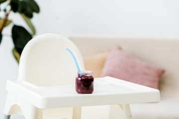 baby food jar with spoon on white highchair in living room