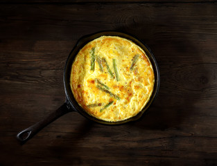 Оmelet with asparagus in a pan on a wooden background. rustic style. top view.