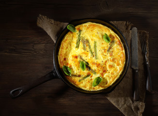 Оmelet with asparagus in a pan on a wooden background. rustic style. top view.