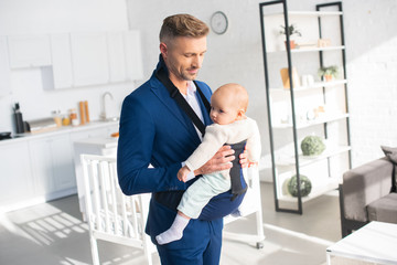 handsome businessman holding infant daughter in room with sunlight