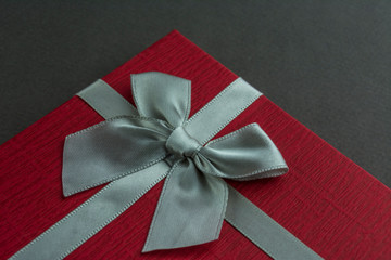 Red gift box with bow grey background. Close up