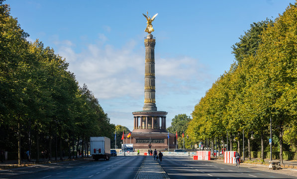 Berlin Victory Column. Golden statue of angel tries to touch the sky. Clouds, trees background.