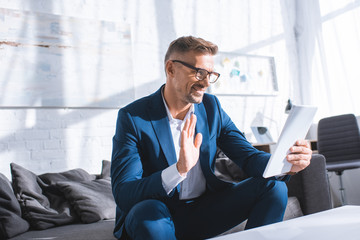 happy businessman waving while having video call on digital tablet