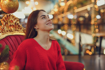 Pretty girl wear red, enjoing her time indoor Christmas place with lights. Copy space