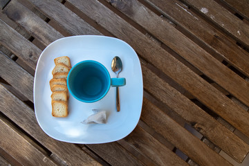 Blue cup of hot wather with fiter tea top view on wooden table background brown saucer and teaspoon small slices of toast breakfast on the terrace snack nice break from work 