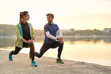 Young man and woman stretching before running