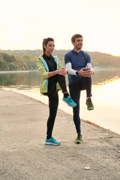 Young man and woman stretching before running