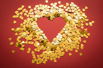 Valentine's Day, Gold hearts are scattered on a red background in the form of a symbol of love.