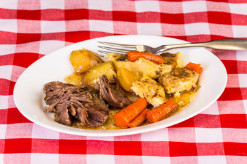Pot Roast Dinner on White Plate with Vegetables and Gravy on Kitchen Table