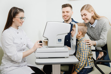 Pediatric Doctor ophthalmologist checks vision of child boy. Concept selection of glasses lenses.