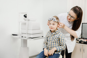 Child reception doctor ophthalmologist selects glasses of lens, check eye sight.