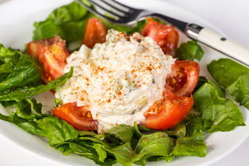 Tuna Salad on Sliced Tomato on plate of Romaine Lettuce.