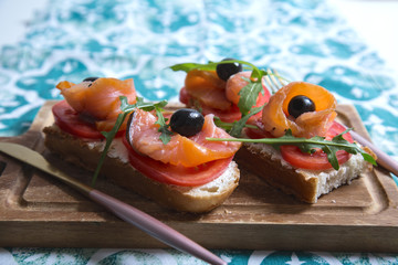 Healthy snack or salmon fish, arugula, olives and creamy cheese on toast bread. French or italian...
