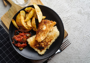 Fried fish with tomato-olive sauce and potatoes.