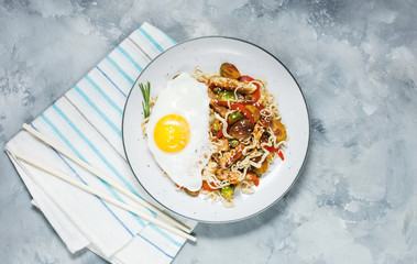 Udon stir-fry noodles with chicken on concrete background