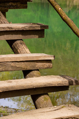 Steps of the elevated wooden walkway along Zlatna Panega River at Iskar-Panega Eco-path Geopark, partial view against the river water surface