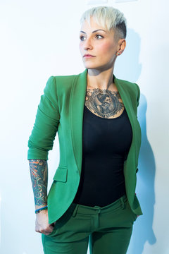 Bellissima ragazza bionda con tatuaggi nel petto e nelle braccia, vestita con una giacca verde
