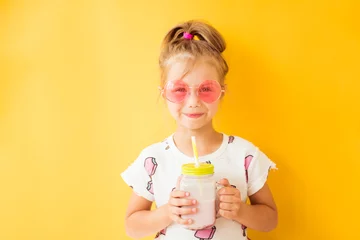 Foto op Plexiglas Milkshake Little girl standing with milkshake in hand on yellow background