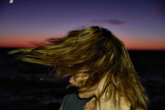Woman shaking head against night sky and sea