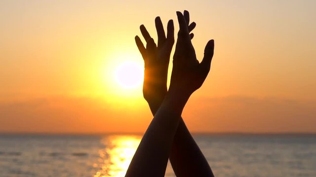 Girl dancing with her arms to heaven against background on sea urface, ocean beach water outside outdoors at sunrise or sunset, Close up. Sun summer nature hands dance dancer happy holiday slow-motion