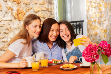Mother and daughter taking selfie during breakfast