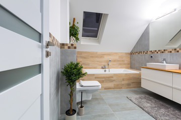 Modern bathroom interior with gray tiles and wooden decors
