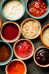 Set of different sauces on black wooden background.