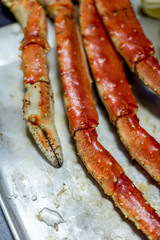 King snow crab's claw with lemon at metal tray on black background