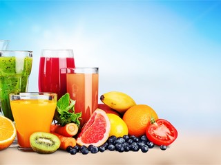 Composition of fruits and glasses of juice on blurred natural