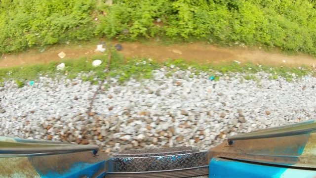 Stairs of doors of moving indian train pebble and piece of garbage on graund