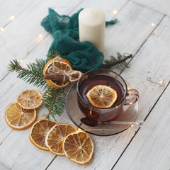 Fototapeta na wymiar cup of tea with dried oranges chopsticks cinnamon candles napkin on a white wooden table