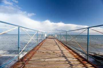 abstract sea background with empty pier, wide horizon, waves and blue sky