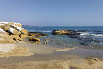 Winter sea view in the village of Ravda, Bulgaria. January icicles with snow on sea rocks.