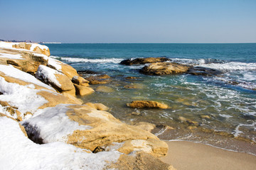 Winter sea view in the village of Ravda, Bulgaria. January icicles with snow on sea rocks.