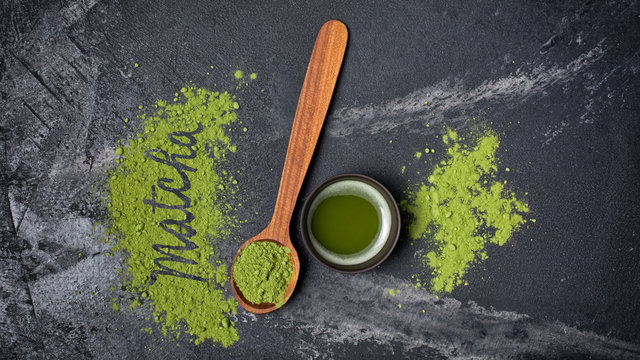 Fototapeta Top view on organic green matcha tea in black ceramic cup with wooden spoon