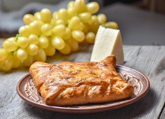 Traditional bread pita or khachapuri on the table with herbs. Homemade baking recipe.