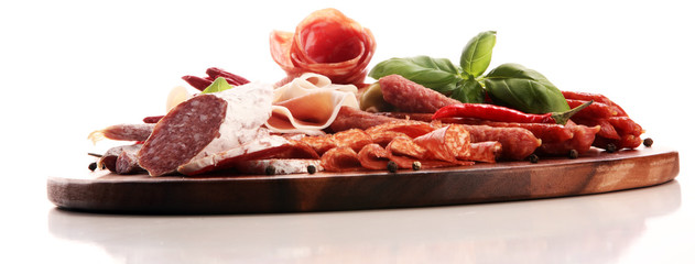 Food tray with delicious salami, pieces of sliced prosciutto crudo, sausage and basil. Meat platter...