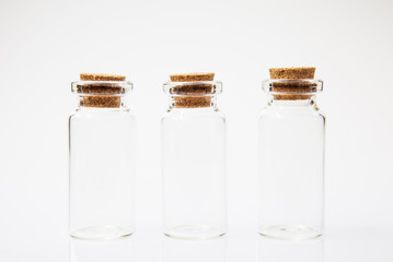 Empty little bottles with cork stopper on white background, close-up