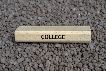wooden board on small pebbles on which the word COLLEGE is shown.