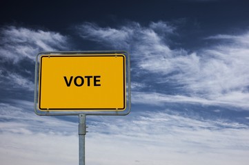 sign showing the word VOTE, in the background is a stormy blue sky