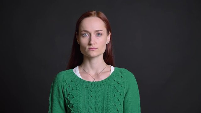 Closeup of beautiful caucasian female with red hair looking straight at camera with neutral facial expression