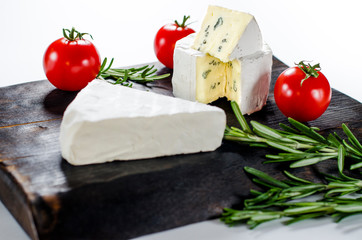 Assorted cheeses on wooden board. Camembert, cheese with blue mildew, mozzarella with tomatoes