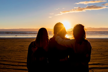 Three Friends Silhouetted at the Beach at Sunset