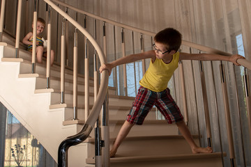 Cute blonde boys play on stairs inside house. Children are happy together on vacation.