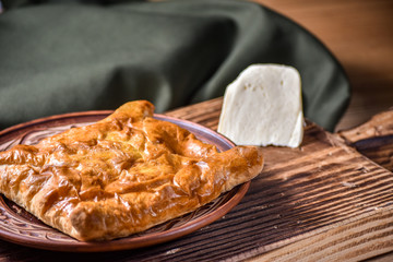 Traditional bread pita or khachapuri on the table with herbs. Homemade baking recipe.