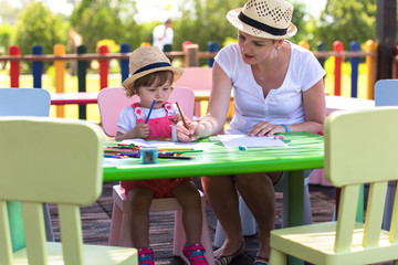 mom and little daughter drawing a colorful pictures