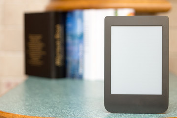 Modern e-book on the background of a stack of thick paper books. Close-up with selective focus. Training and technology concept