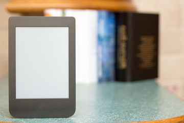 Modern e-book on the background of a stack of thick paper books. Close-up with selective focus. Training and technology concept